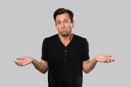 表示怀疑一个穿着黑色t恤衫的男人耸耸肩表示怀疑.照片