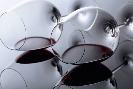 Glasses of red wine on a black reflective background. 