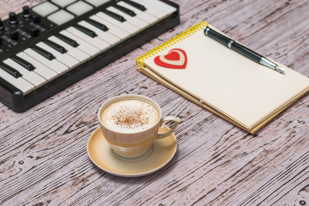 一个音乐调音器，一杯咖啡和一个放在木桌上的笔记本。