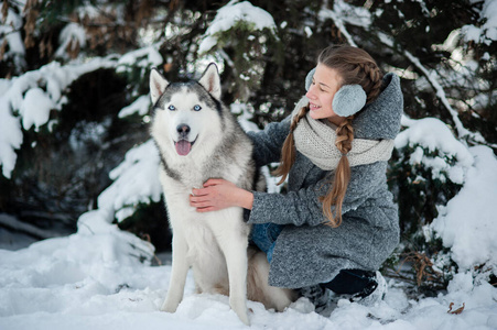 美丽的小女孩和西伯利亚哈士奇在冬天的森林里。2018年新年的象征