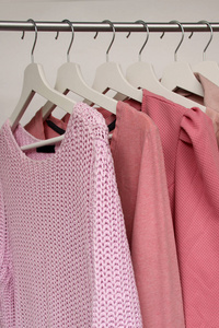 一套粉红色的女装挂在不同颜色的衣架上，一种时尚购物的概念，垂直