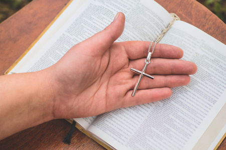 Woman holding a the cross in hand against the background of the 