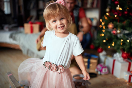  smiling girl near the Xmas tree playing.