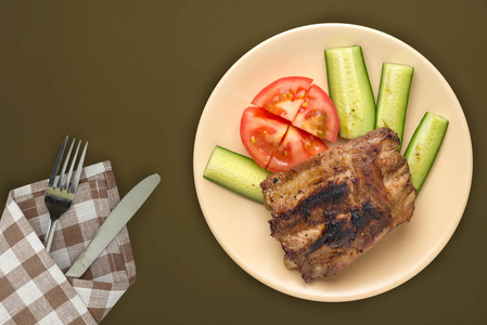  fried pork ribs with chopped cucumbers and tomatoes on a beige 