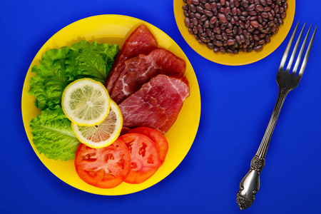  ham with lettuce, tomatoes and lemon on a yellow plate. ham on 