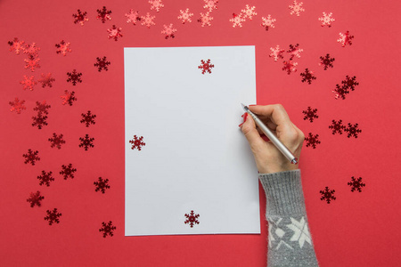 女人写下新年的目标清单计划和梦想。圣诞愿望清单上的红色节日装饰。