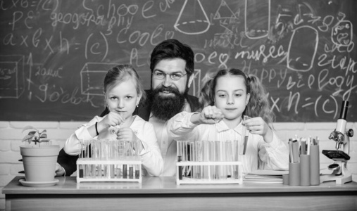 有趣的生物课。在生物教室里，满脸胡须的老师在用显微镜和试管工作。学校生物实验。给孩子们讲解生物学。如何激发孩子们的学习兴趣