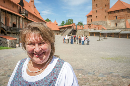 Mature plump woman walks in an old castle, smiles 