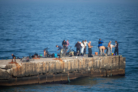 码头上的人在秋天的海边钓鱼-乌克兰-敖德萨-2019年10月17日照片