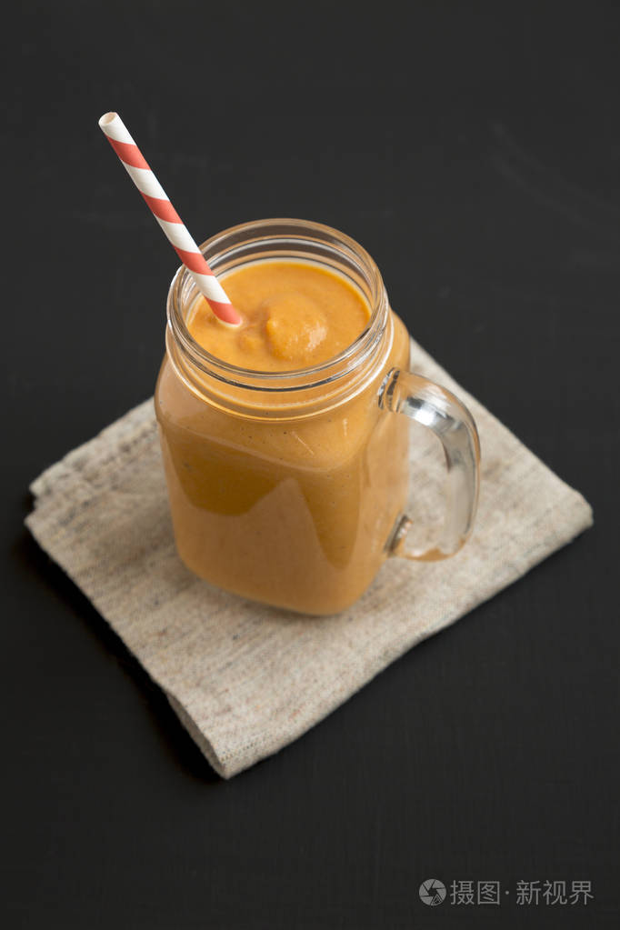 自制南瓜冰沙装在一个玻璃罐里,杯子在黑色表面