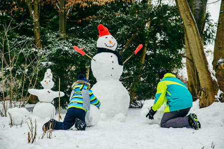 可爱的小男孩在堆雪人。滚大雪球