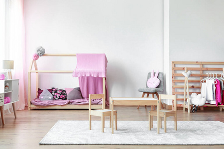在时尚的粉红色和明亮的婴儿房里，在空白色墙上复制空间，并配有木制家具