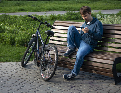年轻的年轻人，带着智能手机和自行车。