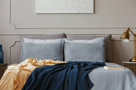 灰色时尚卧室内舒适的双人床上有深蓝色和橙色的毯子