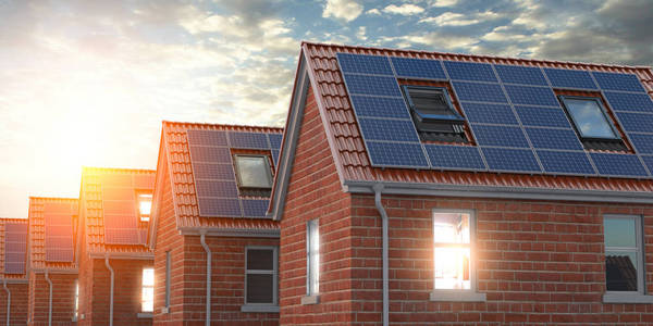一排房子，屋顶上有太阳能电池板，背景是蓝天。