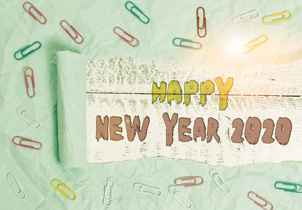写下2020年新年快乐的纸条。商业照片展示问候庆祝节日新的开始最好的祝愿回形针和撕碎的纸板木制经典桌子背景。