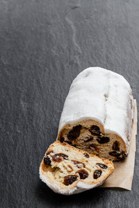 Traditional Christmas stollen fruit cake on black stone table 