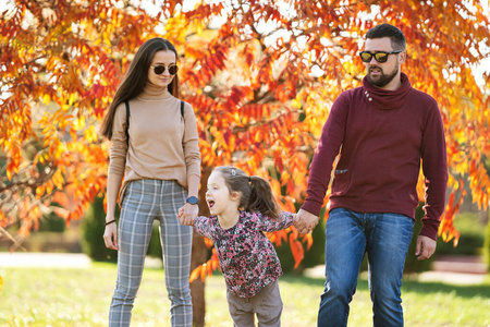 一家人带着女儿在秋天公园散步