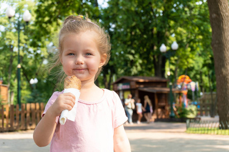 微笑的小女孩在公园里吃冰淇淋