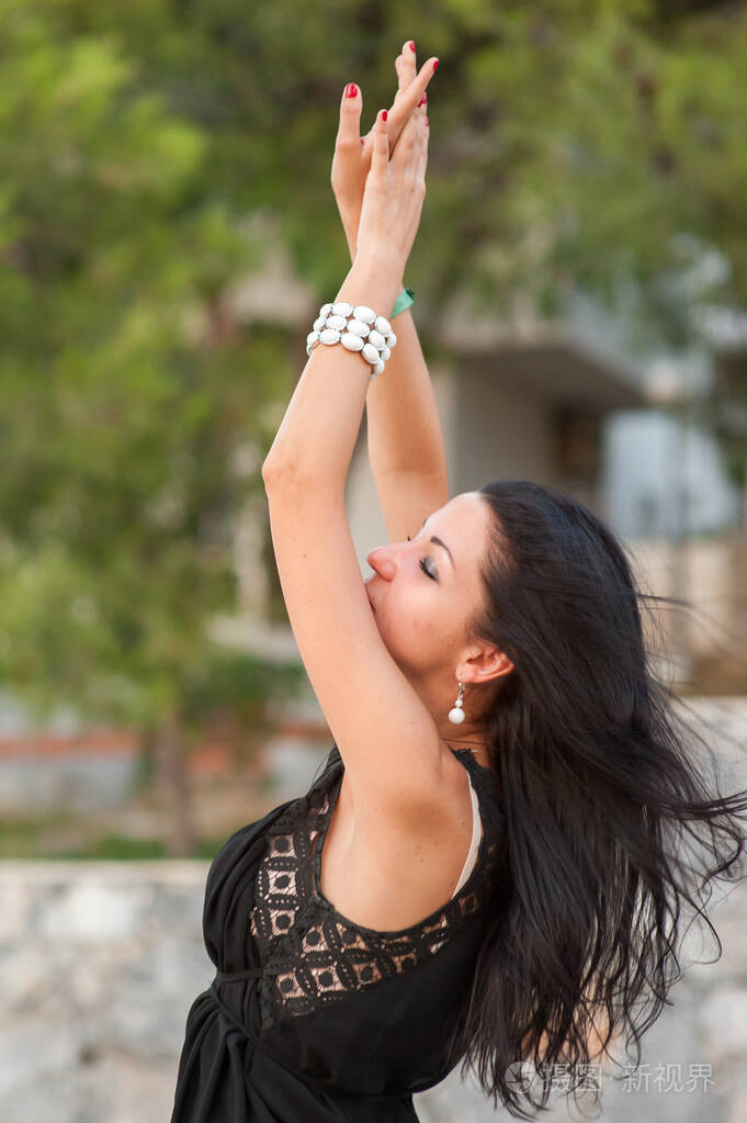 女孩举起双手享受着大自然和风一个漂亮的黑发女人举起双臂跳舞无忧无