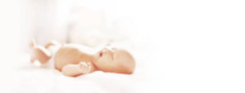 漂亮的新生婴儿躺在床上。带复制空间的模糊文本背景