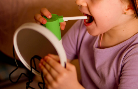 喉咙药药水喷在她喉咙里,一个小女孩的喉咙里喷着药.冷.照片