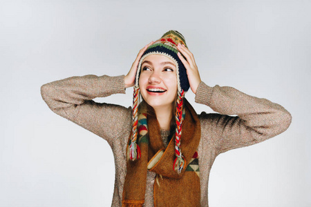 一个戴着北方民族温暖帽子的女孩双手抱着头，开心地笑着