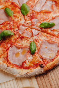 那不勒斯披萨配火腿奶酪芝麻菜罗勒西红柿，在一块木板上撒上奶酪，放在一个牢房的桌布上