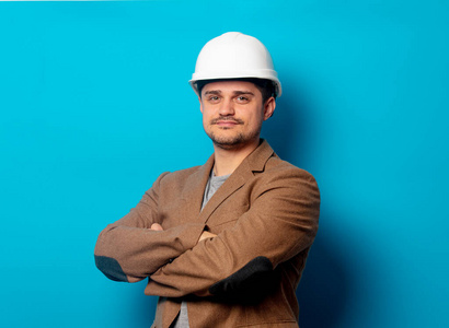 Young  engineer in helmet and jacket on blue background 