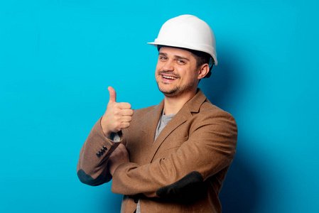 Young  engineer in helmet and jacket on blue background 