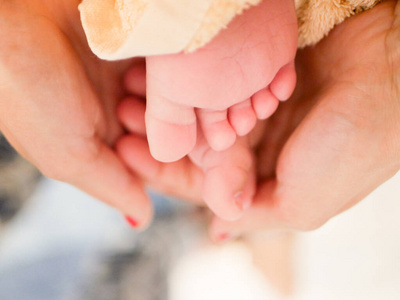 孩子们的腿放在妈妈的手上。新生儿脚的照片。在母亲的怀抱里