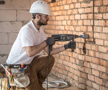 Handyman uses jackhammer, for installation, professional worker 