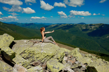 年轻女子坐在岩石上望着地平线。