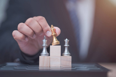 Business man holding golden king chess to winner position 