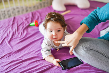 little baby with a phone. on the bed. knowledge of mobile device