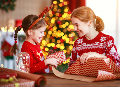 happy family mother and child pack Christmas gifts at home near 