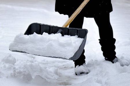 冬天的时候，女人用一把满是雪的铲子铲雪。