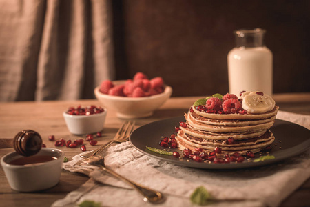 Pancakes with raspberries, banana slices, pomegranate seeds and 