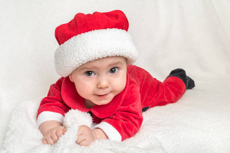 穿着圣诞老人服装的小婴儿躺在白色毯子上