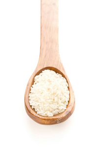 Heap of white uncooked, raw long grain rice in wooden spoon 