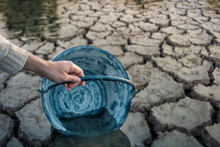 女人的手在龟裂的地上舀水,缺水照片