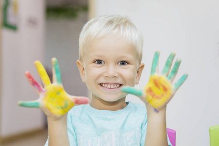 Cheerful little boy showing painted hands 