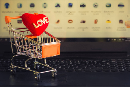 Red heart in a trolley on a laptop keyboard. Ideas about online 
