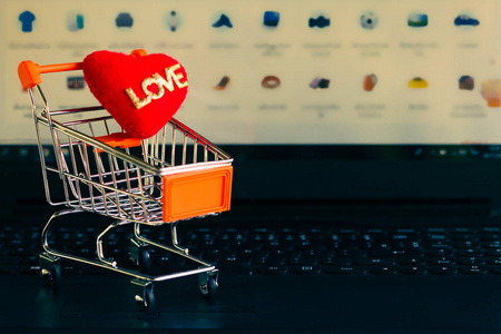 Red heart in a trolley on a laptop keyboard. Ideas about online 