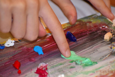 用油画颜料画手指。一个孩子在画家的调色板里戳来戳去