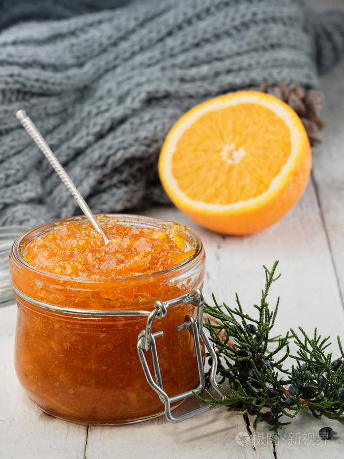 附近有一根针叶树的树枝和半个橘子.一罐果酱里的甜点勺.