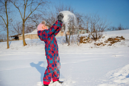 在一个阳光明媚的冬日里，快乐的女孩在扔雪。与雪的积极游戏。寒假。