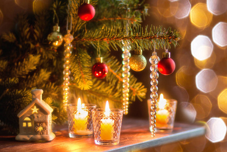 圣诞树下的木桌上点着蜡烛，圣诞树上装饰着圣诞玩具，背景是波基灯