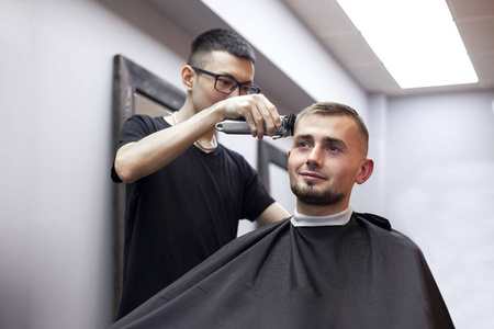 哈萨克理发师用理发器给顾客剪短发,男人在理发店理发,男人在理发店做