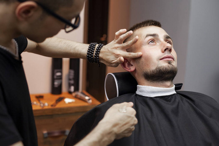 理发店理发,一个年轻人用剃须刀刮胡子,特写照片